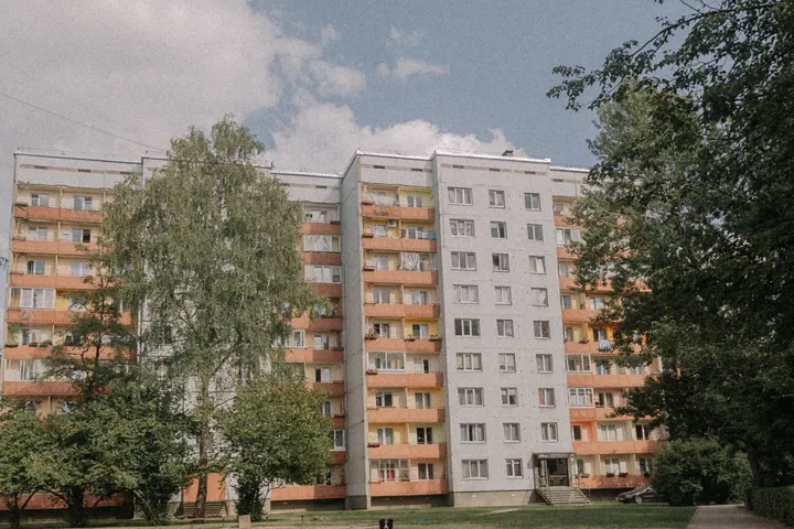 Панельний житловий будинок і зелений двір з доріжкою